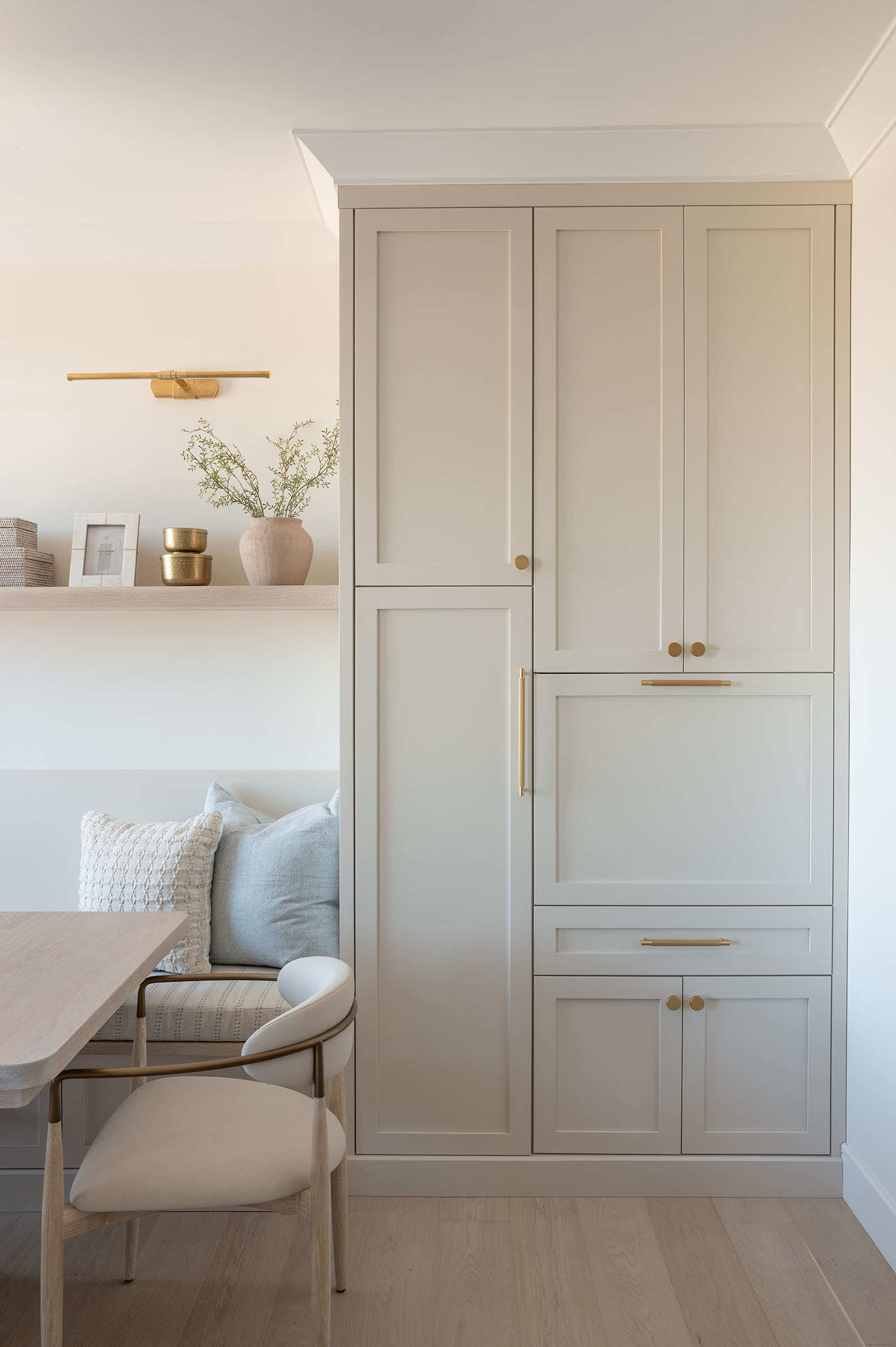 Custom floor to ceiling greige pantry cabinet with drop-down desk that opens and brass handles at The Grandview apartment in North Bethesda MD by Sho and Co Cabinetry