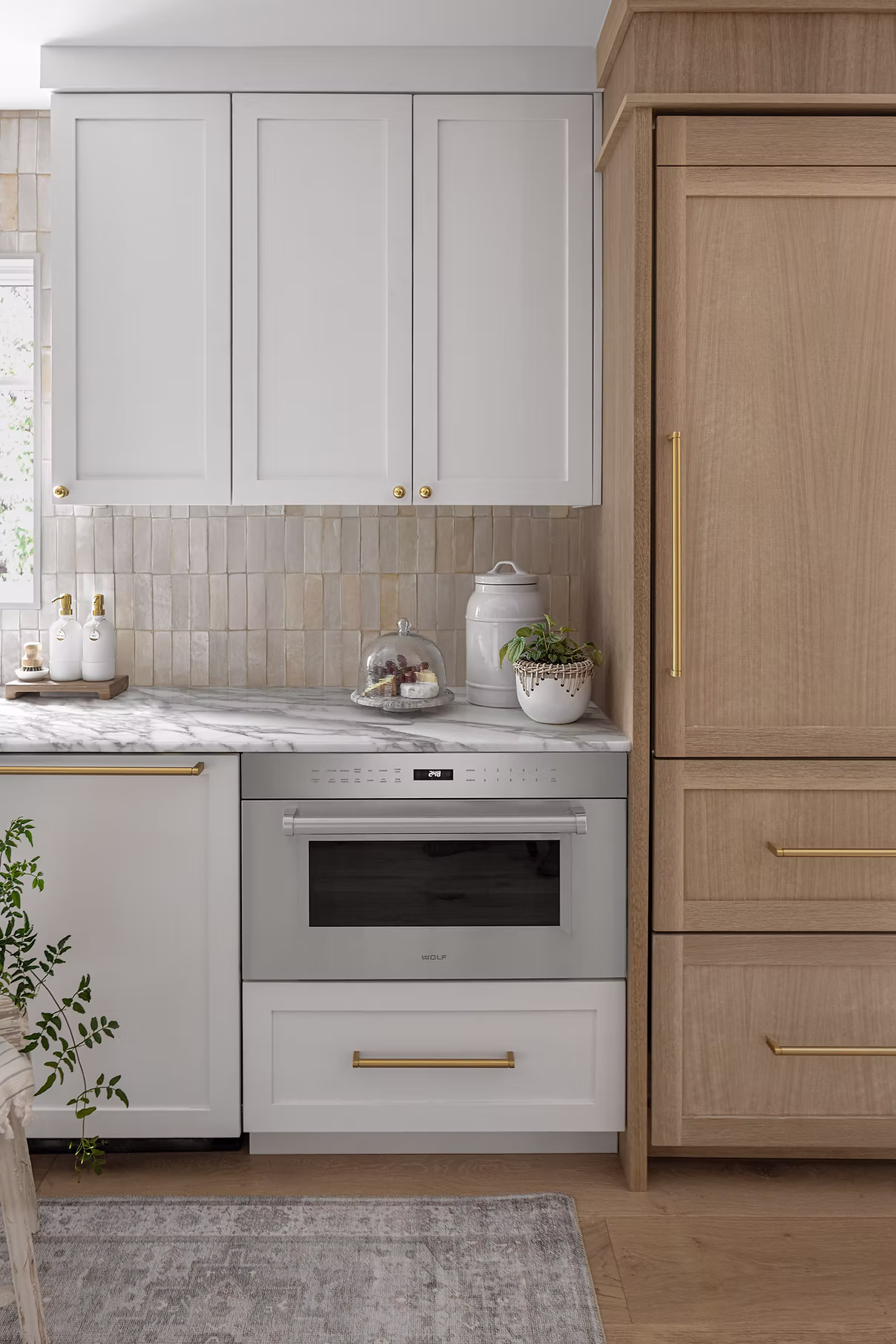 Close up detail of Full Circle project kitchen wall in Potomac MD showing custom white cabinets, brass hardware, vertical tile backsplash, and Wolf microwave drawer