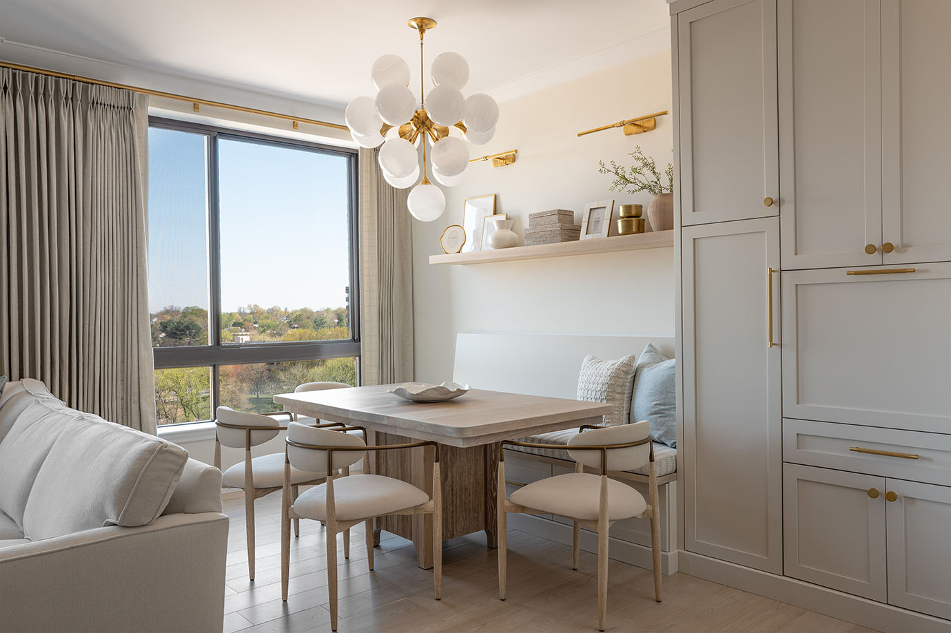 The Grandview apartment dining room in North Bethesda MD featuring custom banquette cabinetry, greige pantry storage, and modern globe chandelier by Sho and Co Cabinetry